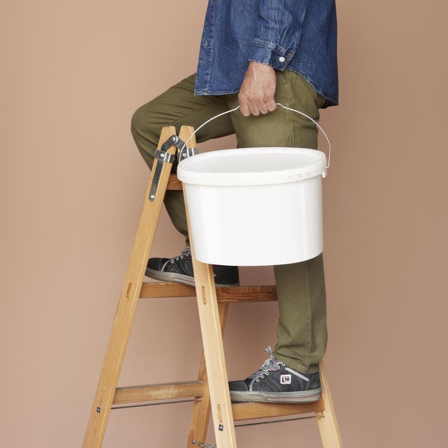 Man on a ladder holding a white ALPLAindustrial bucket